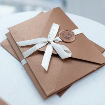 Gift Certificate, gift voucher or discount. closeup bronze invitation envelopes on white table