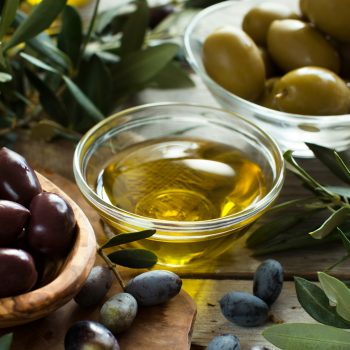 Olive oil and olives on wood background