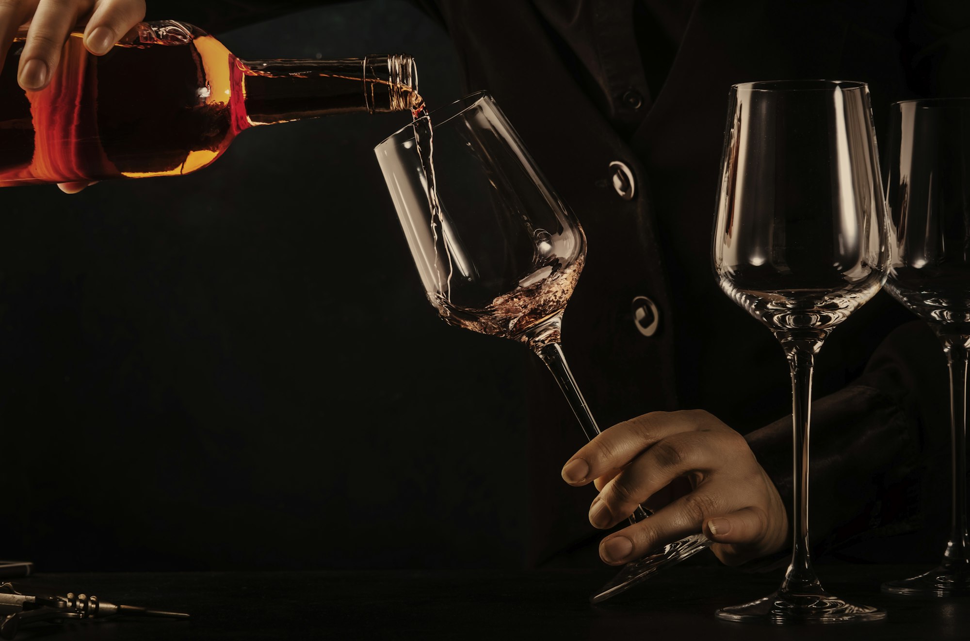 Sommelier pouring rose wine into glass at wine tasting in winery, bar or restaurant