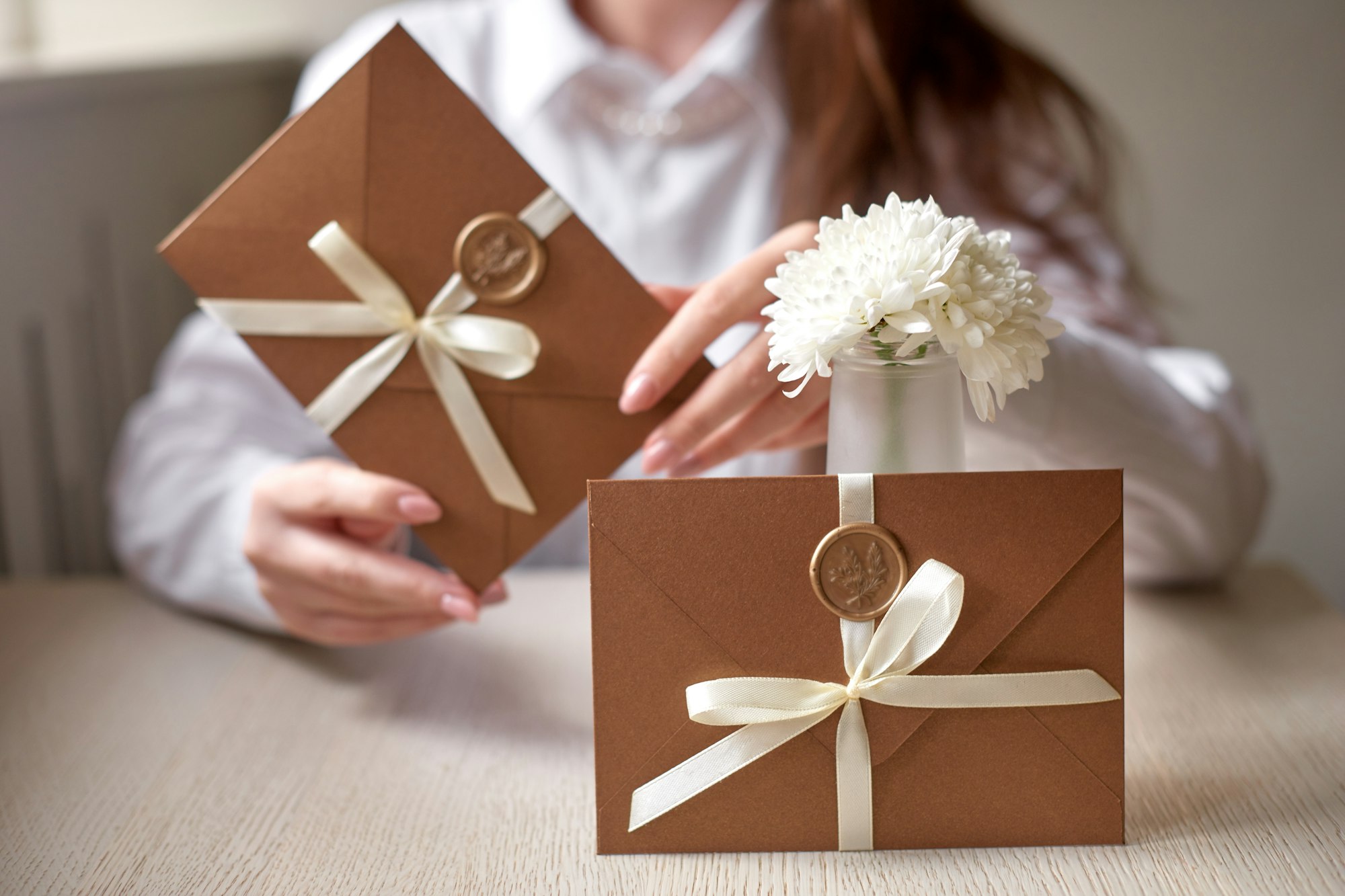 woman holding bronze gift certificate, invitation envelope with wax seal, wedding invitation card